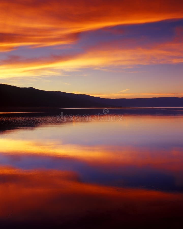 Meravigliosamente nuvole vaporose riflettere gli ultimi raggi dorati del sole su una splendida sul lago.