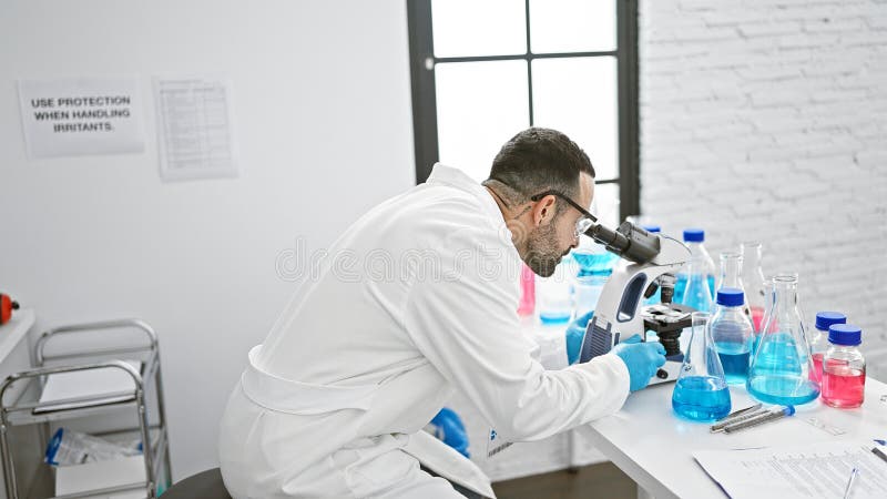Wissenschaftler analysieren Proben mit einem Mikroskop in einem Labor mit Labormantel und Handschuhen
