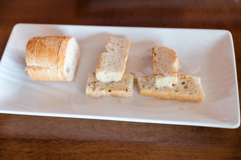 Wit Italiaans heerlijk artisanaal brood met op een witte plaat stock afbeelding Wit Italiaans heerlijk artisanaal brood met op een witte plaat stock afbeelding