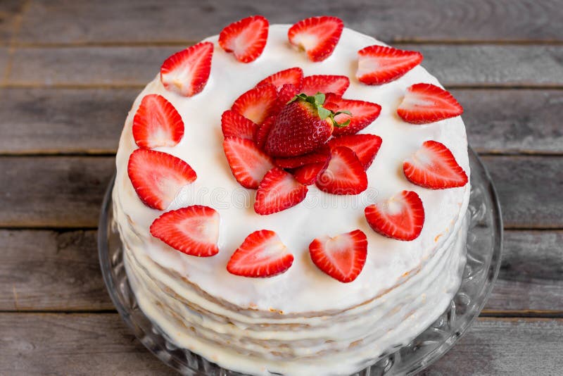 Witte die cake met aardbeien wordt verfraaid op een houten lijst worden geplaatst stock afbeelding Witte die cake met aardbeien wordt verfraaid op een houten lijst worden geplaatst stock afbeelding