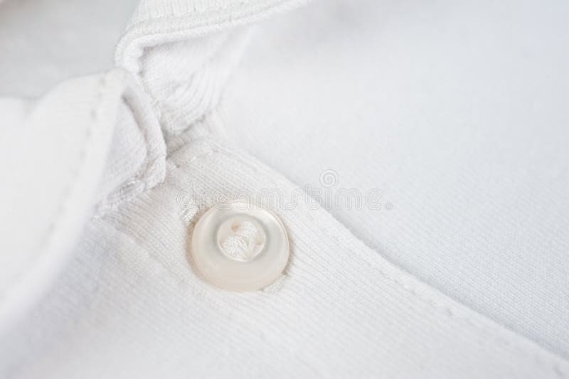 White button sewn on a woolen fabric shot close-up. White button sewn on a woolen fabric shot close-up.