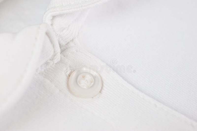 White button sewn on a woolen fabric shot close-up. White button sewn on a woolen fabric shot close-up.