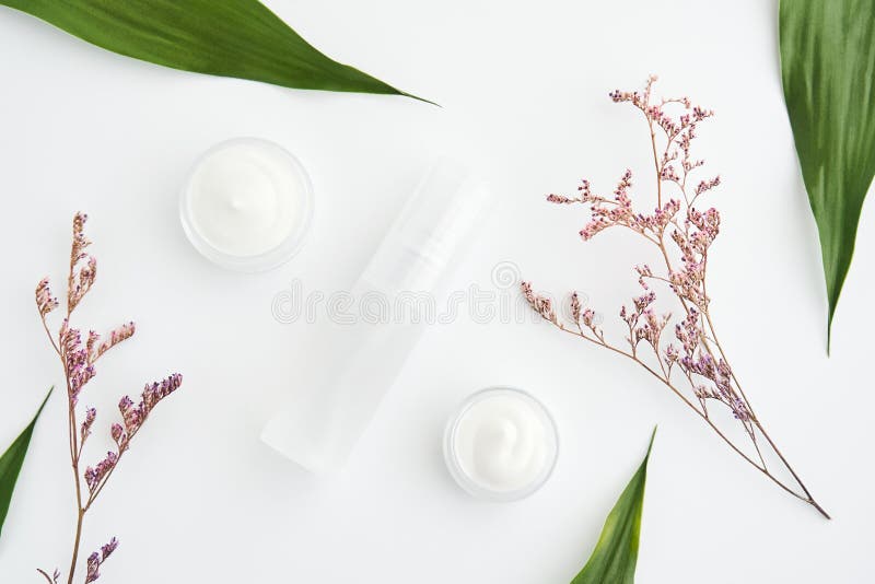 Witte die roomfles, Leeg etiketpakket voor spot omhoog op een groene gebladerteachtergrond wordt geplaatst en bloemen royalty-vrije stock fotografie Witte die roomfles, Leeg etiketpakket voor spot omhoog op een groene gebladerteachtergrond wordt geplaatst en bloemen royalty-vrije stock fotografie