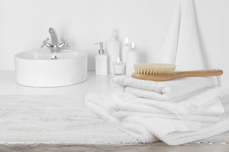 Witte handdoeken op houten lijst over vage eenvoudige badkamersachtergrond stock fotografie Witte handdoeken op houten lijst over vage eenvoudige badkamersachtergrond stock fotografie
