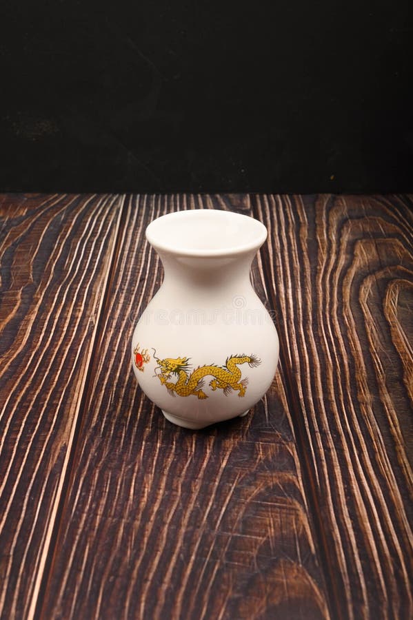 Witte keramische vaas met een patroon in Chinese stijl op een houten achtergrond Sluiten stock fotografie Witte keramische vaas met een patroon in Chinese stijl op een houten achtergrond Sluiten stock fotografie