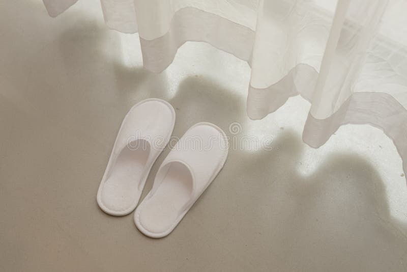 Witte pantoffels door witte zuivere gordijnen en zacht zonlicht royalty-vrije stock fotografie Witte pantoffels door witte zuivere gordijnen en zacht zonlicht royalty-vrije stock fotografie