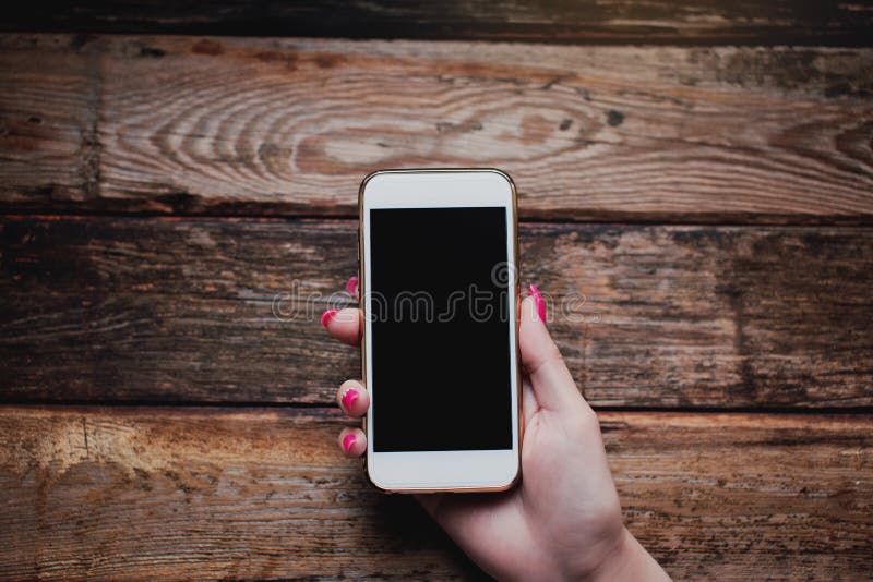 Witte smartphone in vrouwelijke handen op een houten achtergrond royalty-vrije stock foto's Witte smartphone in vrouwelijke handen op een houten achtergrond royalty-vrije stock foto's