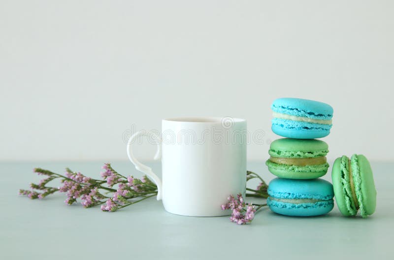 Witte uitstekende kop van koffie en kleurrijke macaron of makaron over pastelkleur houten lijst royalty-vrije stock afbeeldingen Witte uitstekende kop van koffie en kleurrijke macaron of makaron over pastelkleur houten lijst royalty-vrije stock afbeeldingen