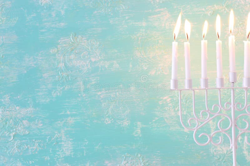 Religion image of jewish holiday Hanukkah background with menorah traditional candelabra and candles over pastel blue background. Religion image of jewish holiday Hanukkah background with menorah traditional candelabra and candles over pastel blue background.