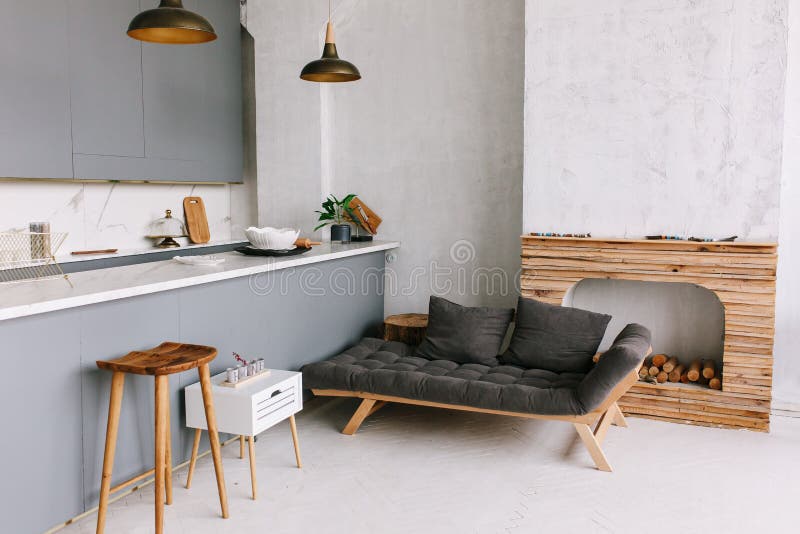 Interior of the modern loft kitchen-studio in the apartment. Room, furniture, sofa near wooden fireplace. Interior of the modern loft kitchen-studio in the apartment. Room, furniture, sofa near wooden fireplace.