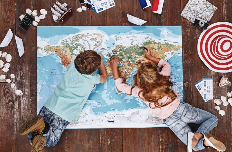 Wo Sie die Kinder besuchen möchten, die Weltkarte, beim Lügen auf ihr, nahe Reiseeinzelteilen betrachten stockbild Wo Sie die Kinder besuchen möchten, die Weltkarte, beim Lügen auf ihr, nahe Reiseeinzelteilen betrachten stockbild