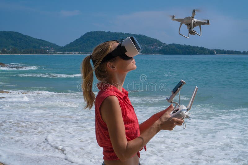 Woan with drone camera and virtual reality glasses taking photos and videos on the beach