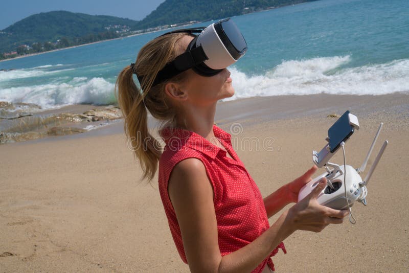 Woan with drone camera and virtual reality glasses taking photos and videos on the beach