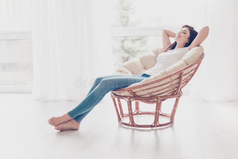 Wochenenden schließlich! Entspanntes Brunettemädchen sitzt auf modernem cha lizenzfreies stockbild Wochenenden schließlich! Entspanntes Brunettemädchen sitzt auf modernem cha lizenzfreies stockbild