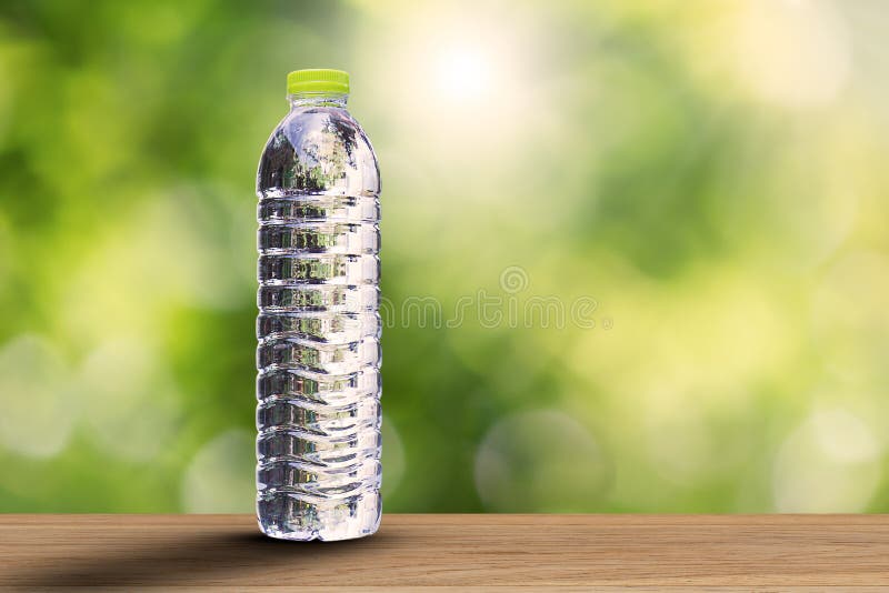 Wody pitnej butelka z miękkim cieniem na drewnianym tabletop na zamazanym zielonym bokeh tle z miękkim światłem słonecznym zdjęcie stock Wody pitnej butelka z miękkim cieniem na drewnianym tabletop na zamazanym zielonym bokeh tle z miękkim światłem słonecznym zdjęcie stock