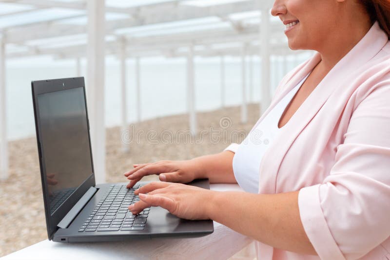 Wolny. portret kaukaskiej uśmiechniętej kobiety pracującej na laptopie. model plus. na zewnątrz. koncepcja zdalnej pracy i obraz royalty free