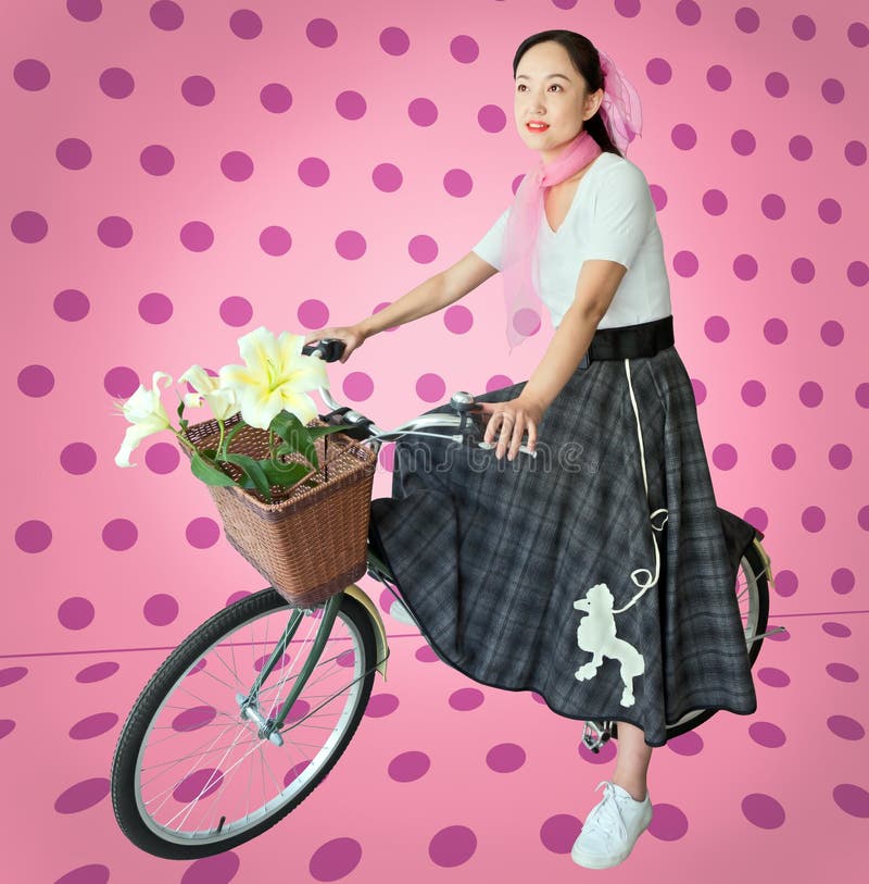 Una donna Cinese indossa un retrò stile del 1950 gonna barboncino come lei cavalca una bicicletta vintage su una polka dot sfondo.