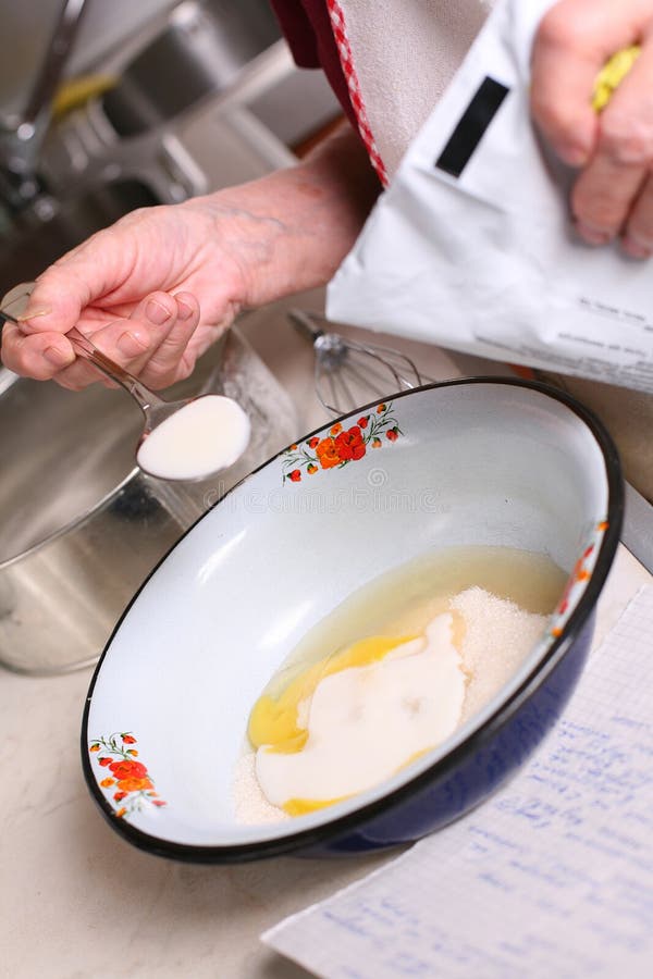 Woman adds milk to the bowl with sugar and broken egg