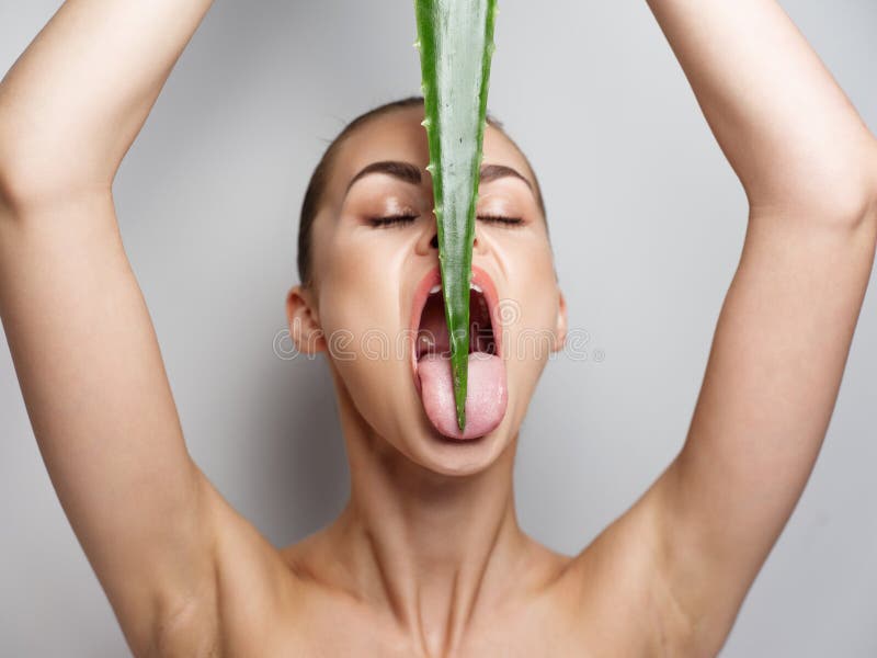 woman with aloe leaf over her head and clean skin cosmetology wide open mouth model. High quality photo