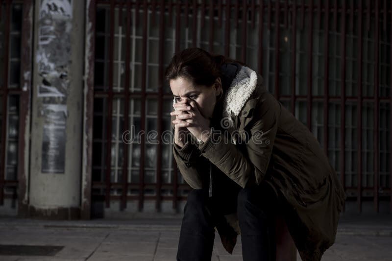 Woman alone in the street suffering depression looking sad desperate and helpless sitting lonely in dirty dark urban background stock photos Woman alone in the street suffering depression looking sad desperate and helpless sitting lonely in dirty dark urban background stock photos