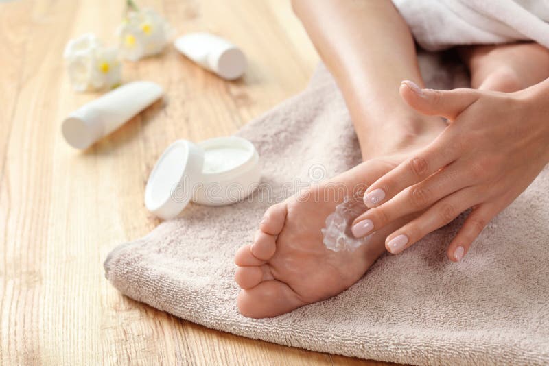 Woman applying foot cream on towel, closeup.