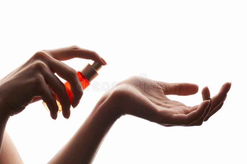 Woman applying perfume on her wrist, bright red perfume bottle, beautiful hands