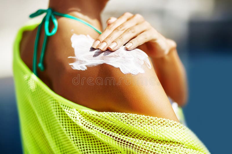 Woman applying sunscreen on her shoulder