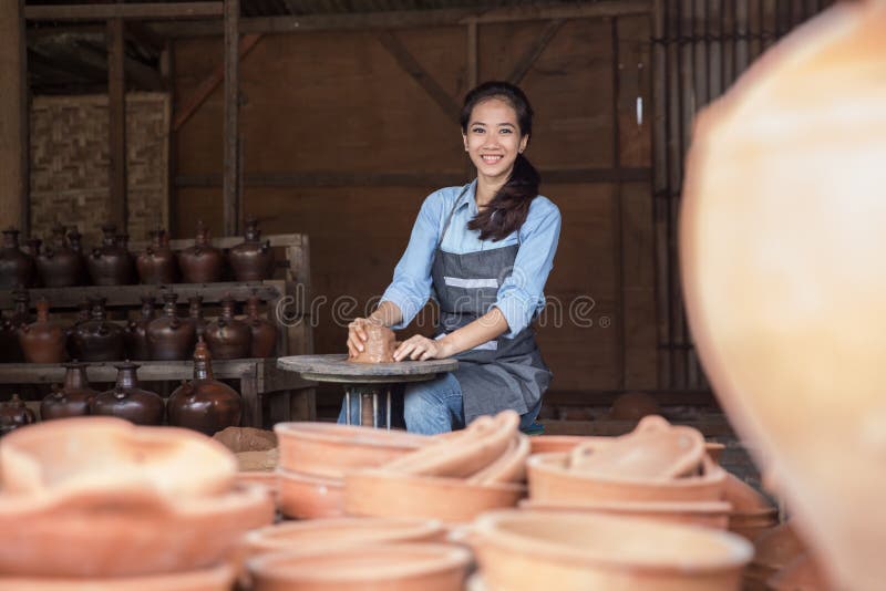 Asian woman making vase from fresh wet clay on pottery wheel. Asian woman making vase from fresh wet clay on pottery wheel