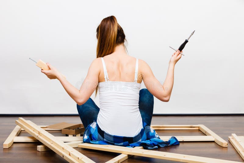 Woman assembling wooden furniture. DIY. Rear view.