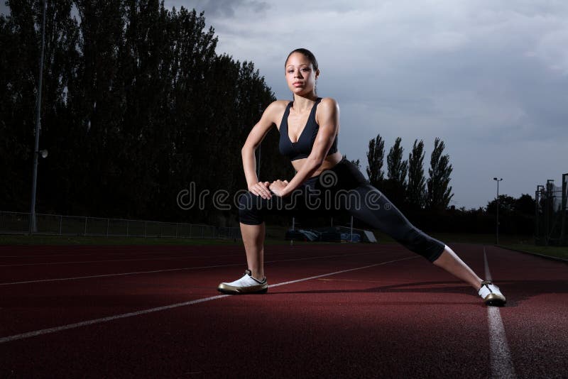 Woman athlete fitness stretch on athletics track