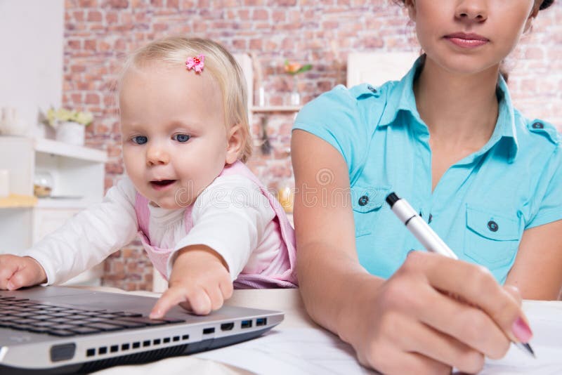 Woman with baby in the kitchen working with laptop