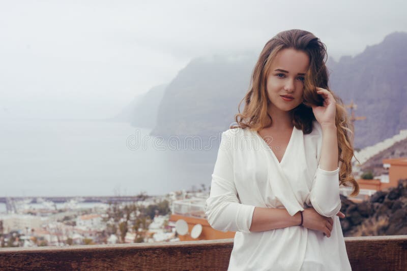 Woman on a background of mountains and a city. Girl travels in Tenerife. The girl in the summer knows the world. stock photography Woman on a background of mountains and a city. Girl travels in Tenerife. The girl in the summer knows the world. stock photography