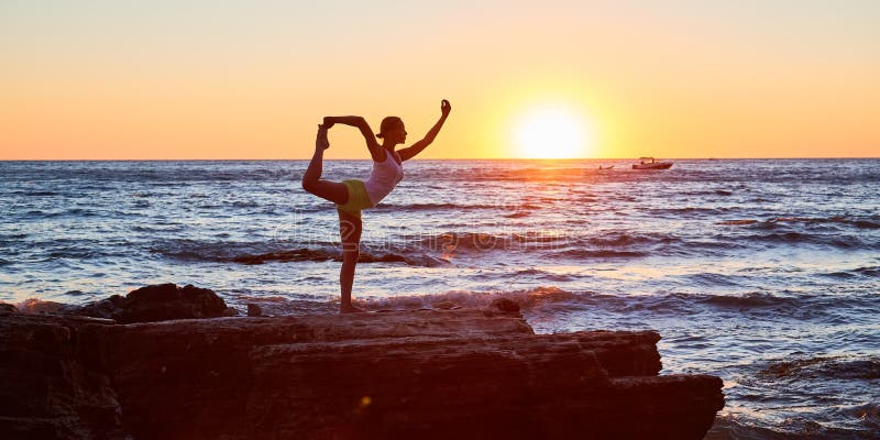 Woman balancing on one leg. Cute sunset view. Ocean landscape and stretch time. Yoga meditation concept, copy space