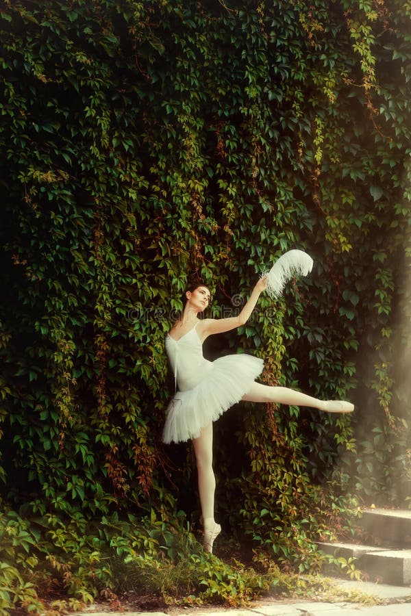 Woman ballerina in a white dress elegantly dances.