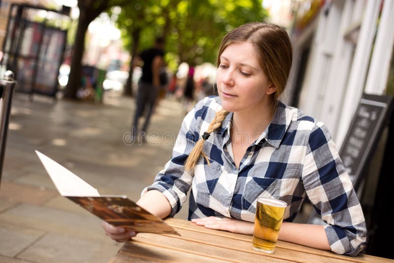 Woman at bar reading menu stock photo. Image of casual - 55284264