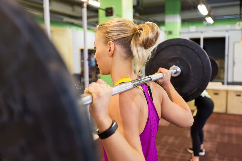 Fitness, sport and people concept - woman with barbell at group training in gym