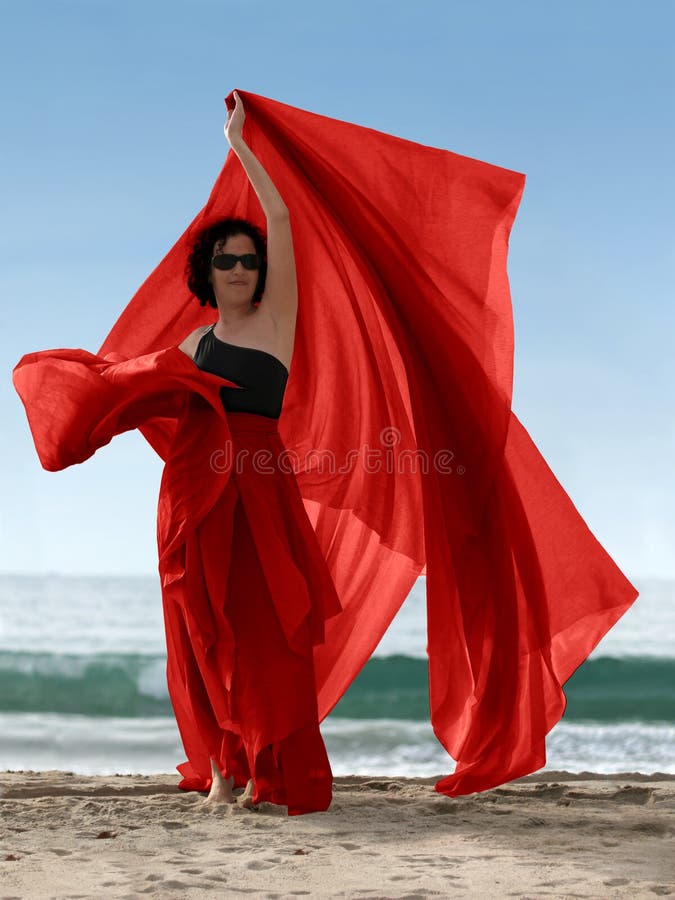 Donna sulla spiaggia con una sciarpa rossa.