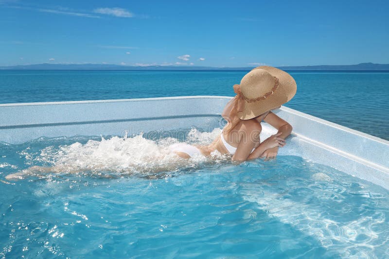 Woman in beach hat enjoying in jacuzzi, swimming pool on Tropical Resort. Exotic Greece Paradise. Travel, Tourism and Vacations Concept.