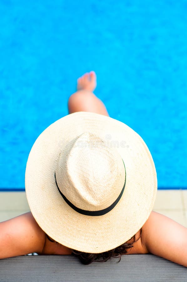 Woman with beach hat relaxing by the pool at exotic resort royalty free stock photo Woman with beach hat relaxing by the pool at exotic resort royalty free stock photo