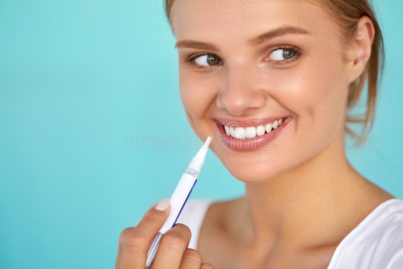 White Smile. Closeup Portrait Of Beautiful Happy Smiling Woman With Perfect Healthy White Teeth Using Teeth Whitening Pen. Dental Health And Beauty, Tooth Care Concept. High Resolution Image. White Smile. Closeup Portrait Of Beautiful Happy Smiling Woman With Perfect Healthy White Teeth Using Teeth Whitening Pen. Dental Health And Beauty, Tooth Care Concept. High Resolution Image