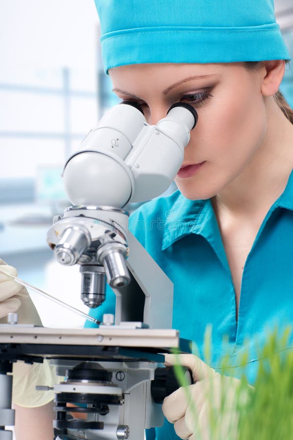 Woman biologist working with microscope stock photo