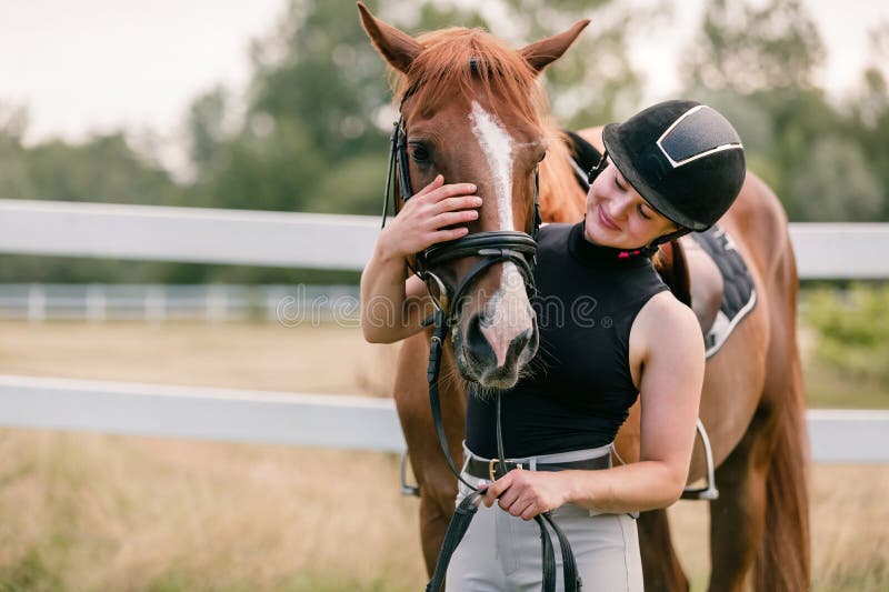 Woman with a black helmet stroking a chestnut horse head, close up shot