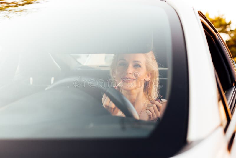Woman blonde driver does make-up in car stock photo