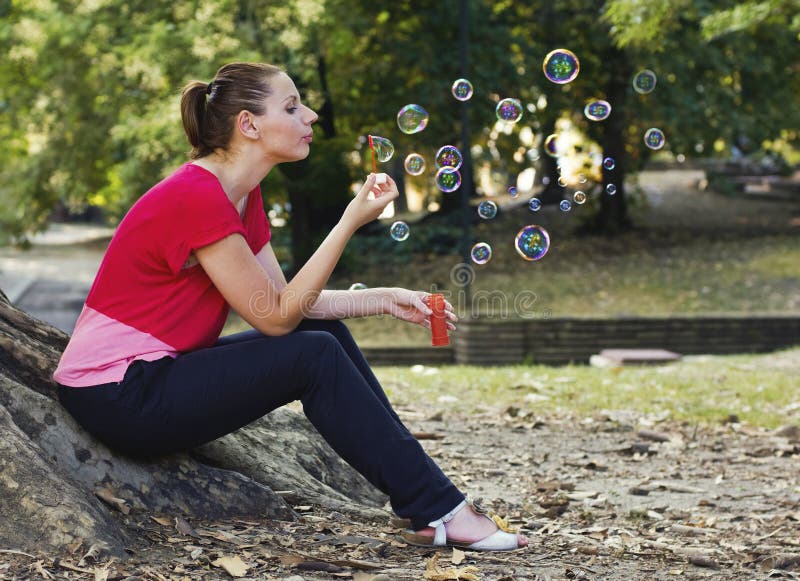 Woman blowing bubbles in park stock images Woman blowing bubbles in park stock images