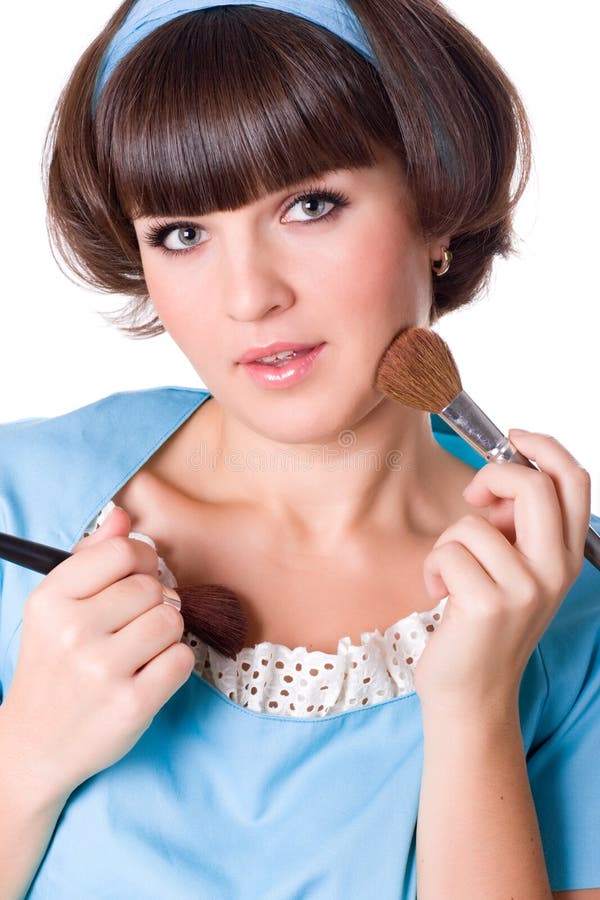 Woman in blue dress with two make-up brushes
