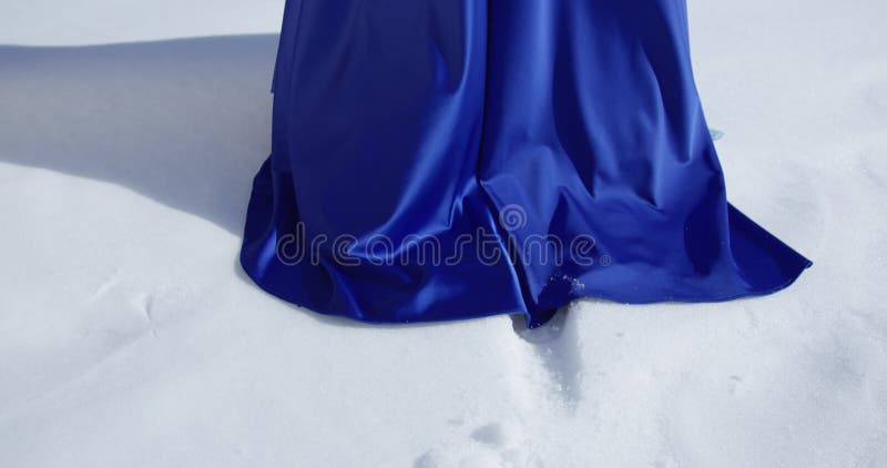 Woman in blue dress is walking on a snow