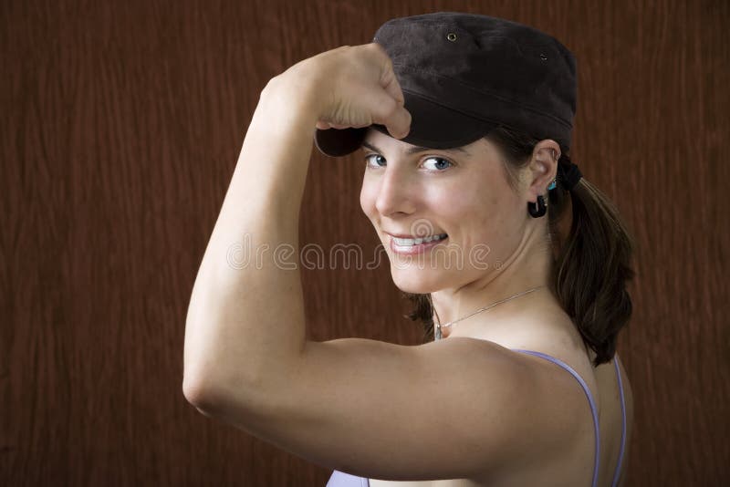 Closeup of woman with blue eyes wearing a cap flexing her bicep. Closeup of woman with blue eyes wearing a cap flexing her bicep