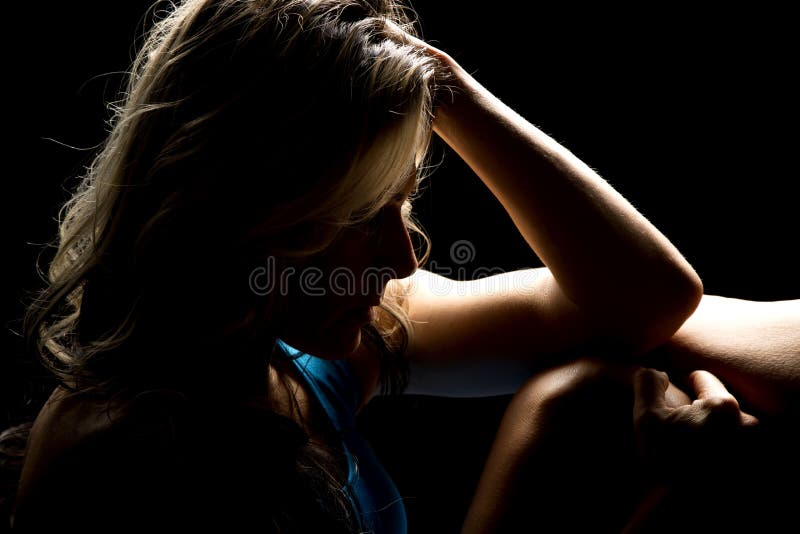 Woman in blue shorts highlighted from back close arm on knee royalty free stock photography Woman in blue shorts highlighted from back close arm on knee royalty free stock photography