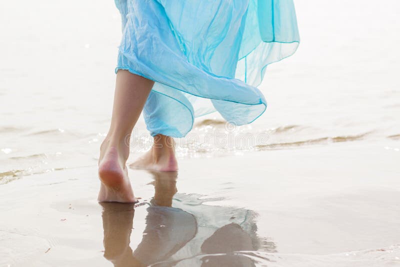 Woman with blue skirt walking on the beach in sunny day