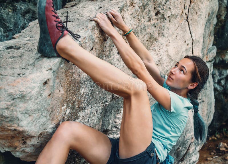 Woman bouldering the rocky stone